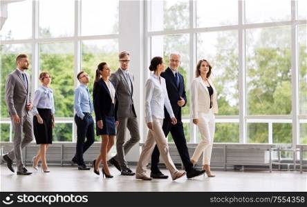people, work and corporate concept - happy business team walking along office building and talking. business people walking along office building