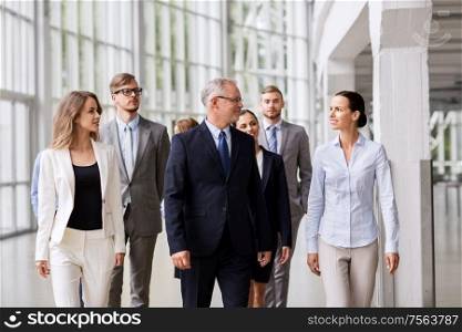 people, work and corporate concept - happy business team walking along office building and talking. business people walking along office building