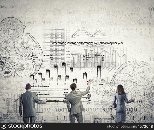 People working in collaboration. Business team standing with back drawing business concepts on wall