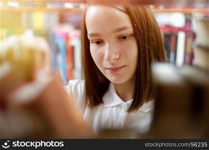 People: young girl, student, chooses a book in a library or bookstore, smiling, sunlight effect.. Girl and books