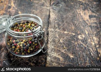 Pepper in a glass jar. On a wooden background.. Pepper in a glass jar.
