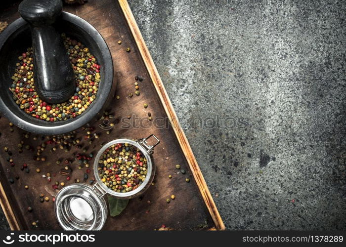 Pepper in a mortar on a wooden tray. On a rustic background.. Pepper in a mortar on a wooden tray.