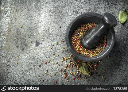 Pepper in a mortar with a pestle. On a rustic background.. Pepper in a mortar with a pestle.