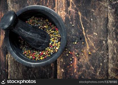 Pepper in a mortar with a pestle. On a wooden background.. Pepper in a mortar with a pestle.