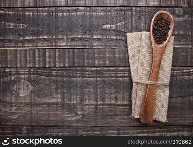 Pepper on spoon and kitchen towel on wooden board. Place for text