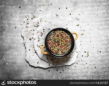Peppercorn in a bowl on the stone plates . On a stone background.. Peppercorn in a bowl