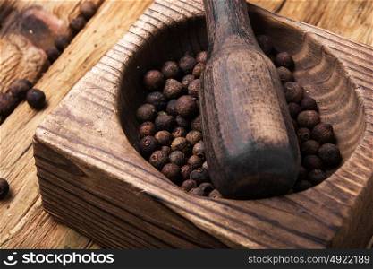 peppercorn in retro wooden mortar. Black fragrant pepper peas in a stylish wooden mortar