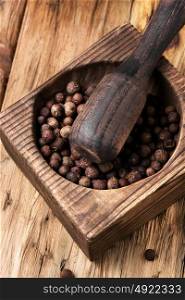 peppercorn in retro wooden mortar. Black fragrant pepper peas in a stylish wooden mortar