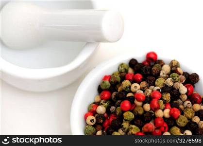 Peppercorns With Mortar And Pestle. Peppercorns in various colors of red, green and the familiar black peppercorn on white with a Mortar and Pestle