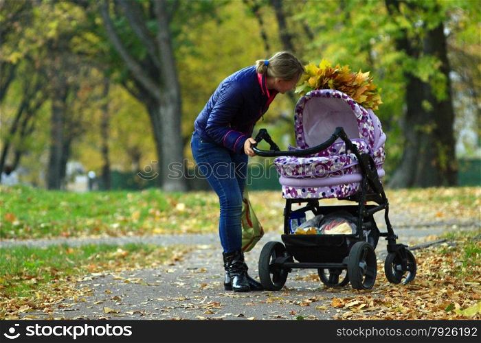perambulator standing in the park and wisp os yellow autumn leaves on it