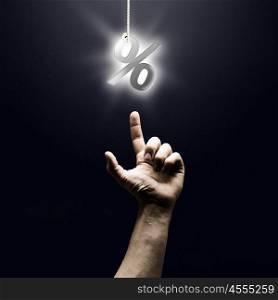 Percent symbol. Human finger pointing at percentage sign on dark background