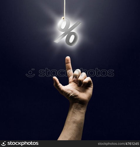 Percent symbol. Human finger pointing at percentage sign on dark background