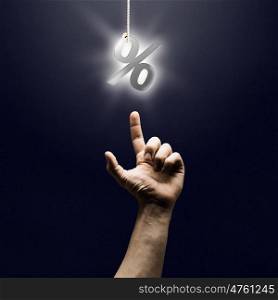 Percent symbol. Human finger pointing at percentage sign on dark background