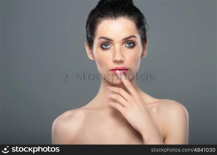 Perfect skin. Beautiful woman's face. Shoulders. Finger near lips.