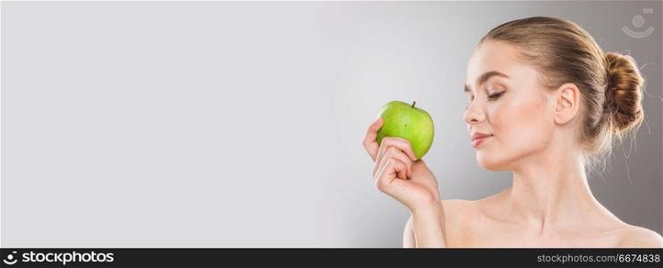 Perfect woman with apple. Beautiful young nude woman with green apple close up on gray background with copy space