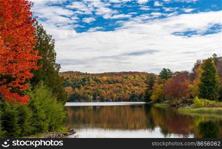 Perfectly calm Silver Lake in Barnard Vermont reflecting the trees during the fall season. Calm reflections of fall trees in Silver Lake Vermont