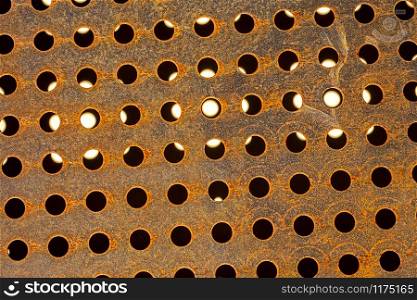 perforated metal with circular holes mostly black, some with translucent white light