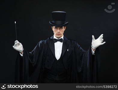 performance, circus, show concept - magician in top hat with magic wand showing trick