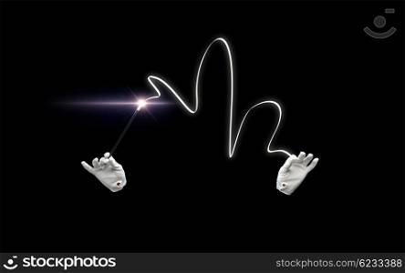 performance, illusion, circus, show concept - magician hands in gloves with illuminating magic wand showing trick over black background