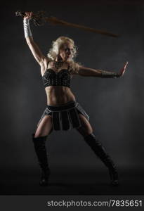 Performer woman wearing sexy costume and holding a sword, grey smoky background