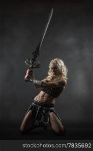 Performer woman wearing sexy costume and holding a sword, grey smoky background