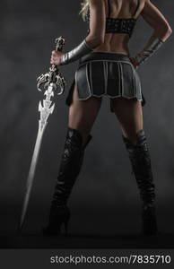 Performer woman wearing sexy costume and holding a sword, grey smoky background