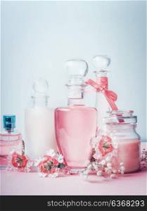 Perfume and cosmetics fleeting scents in pastel color . Composition of bottles with flowers , front view. Beauty, floral perfume and skin care concept