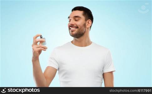 perfumery, beauty and people concept - happy smiling young man with male perfume over gray background