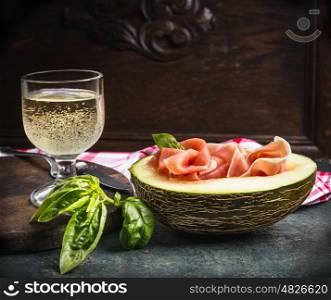 Perl wine glass with ham and melon , Traditional Italian dish on rustic kitchen table, front view