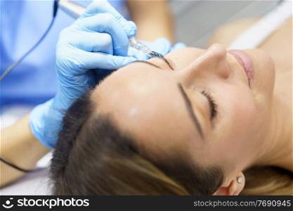 Permanent make-up for eyelashes of beautiful woman in a beauty salon. Close-up of beautician doing tattooing eyelashes. Micropigmentation treatment.. Permanent make-up for eyelashes of beautiful woman in a beauty salon. Micropigmentation treatment.