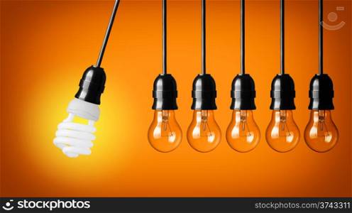 Perpetual motion with light bulbs and energy saver bulb. Idea concept on orange background.