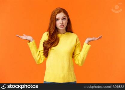 Perplexed cute redhead girl, shrugging with raised arms and looking confused, dont know answer, cant help, feeling confused or indecisive, cannot understand, standing orange background.. Perplexed cute redhead girl, shrugging with raised arms and looking confused, dont know answer, cant help, feeling confused or indecisive, cannot understand, standing orange background