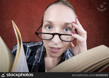 Perplexed woman with big eyes and glasses reading a book.