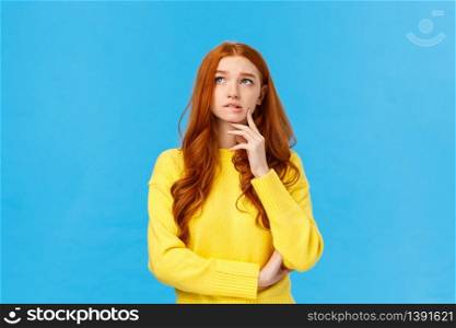 Perplexed, worried and concerned cute redhead student college girl trying choose university, thinking future, looking pensive upper left corner, bite lip and frowning, thoughtful over blue background.. Perplexed, worried and concerned cute redhead student college girl trying choose university, thinking future, looking pensive upper left corner, bite lip and frowning, thoughtful over blue background