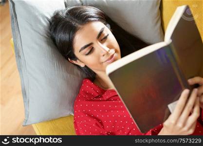 Persian woman at home reading on a couch wearing pyjamas. Persian woman at home reading on a couch