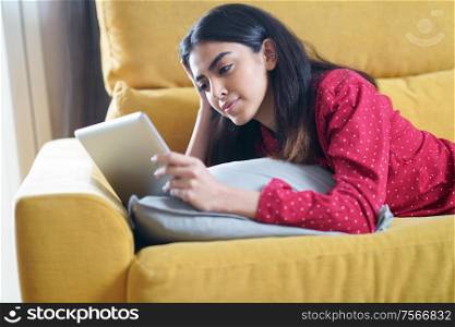 Persian woman at home using digital tablet on a couch. Persian woman at home using digital tablet