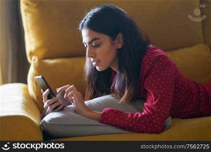 Persian woman at home using smartphone on a couch. Persian woman at home using smart phone