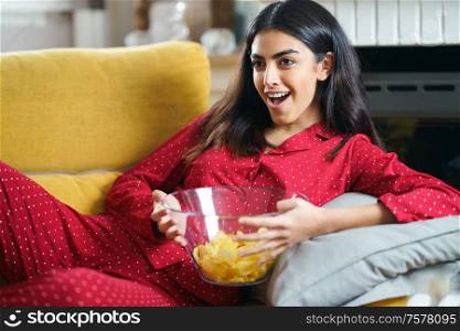 Persian woman at home watching TV. Girl eat chips potatoes. Persian woman at home watching TV eating chips potatoes