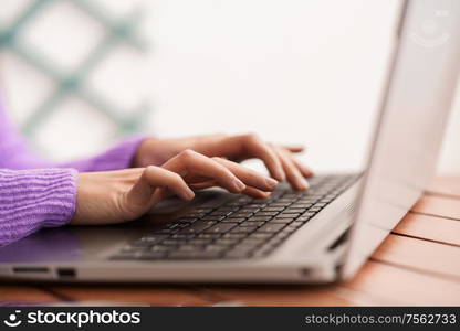 Persian woman sitting in an armchair on her balcony using laptop computer. Persian woman on her balcony using laptop computer