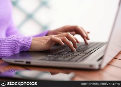 Persian woman sitting in an armchair on her balcony using laptop computer. Persian woman on her balcony using laptop computer