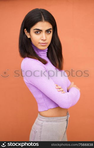 Persian woman standing outdoors on red wall background. Persian woman standing outdoors on red wall