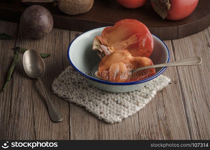 Persimmon fruit on rustic table in vintage style.