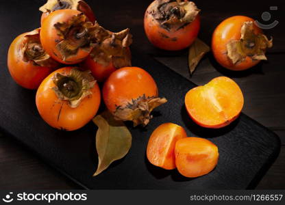 Persimmon still life in low key. Organic Kaki fruit harvested in autumn. Diospyros kaki