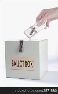 Person&acute;s hand inserting a mouse trap into a ballot box