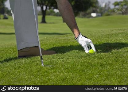 Person&acute;s hand picking up a golf ball