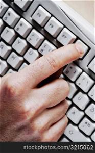 Person&acute;s hand pressing a computer key