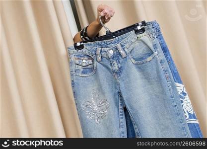 Person&acute;s hand showing a jeans through curtains