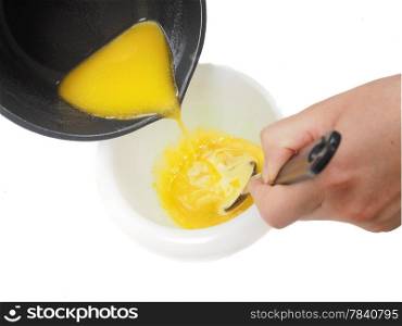 Person adding melted butter from kettle into blend in plastic bowl whilst stirring