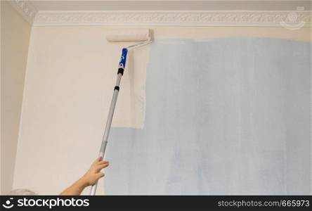 Person appplying paint on wall using roller brush. Home renovation concept.. Person applying paint on wall