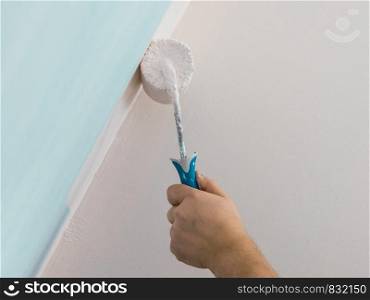 Person appplying paint on wall using roller brush. Home renovation concept.. Person applying paint on wall